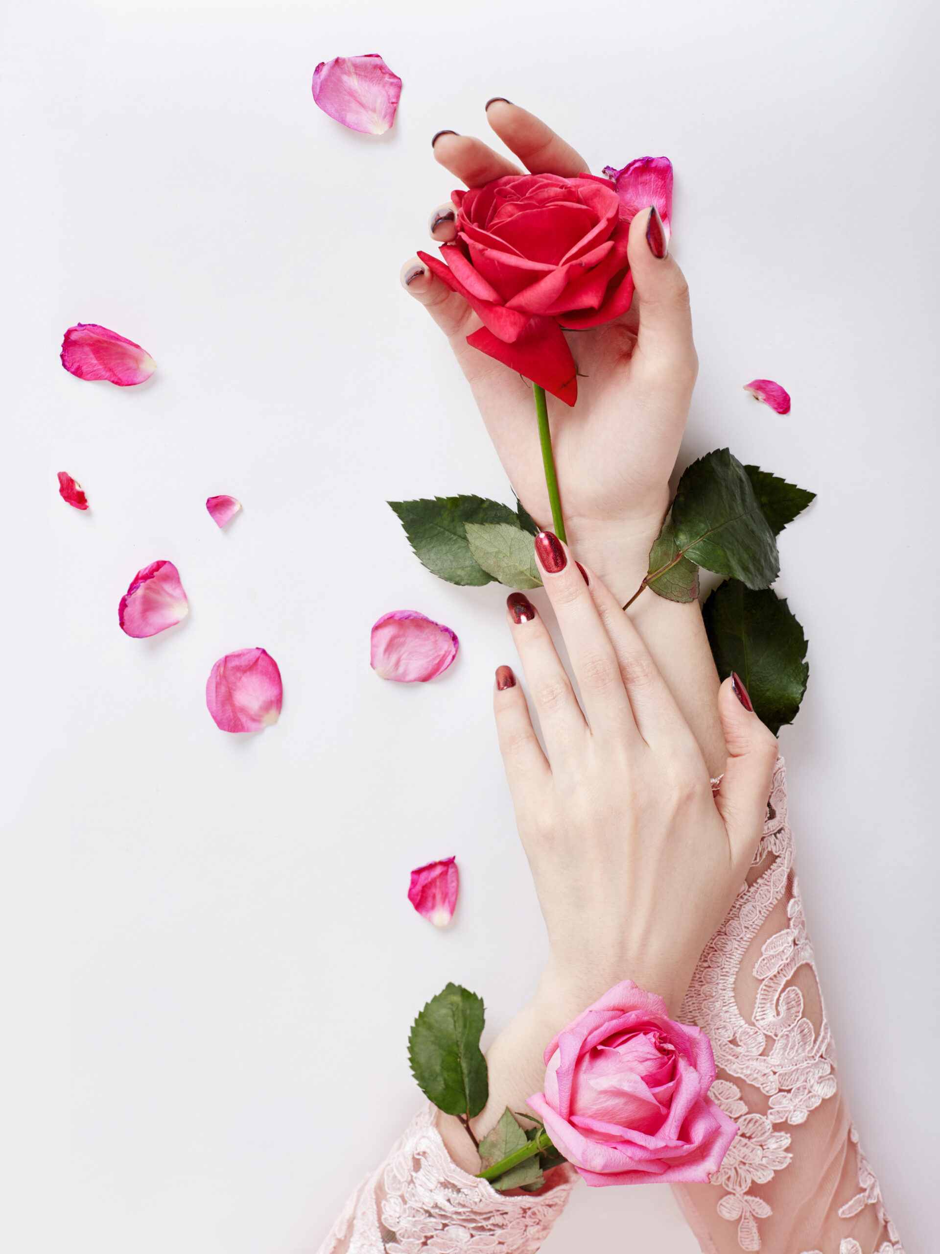 Fashion art portrait woman in summer dress and flowers in her hand with a bright contrasting makeup. Creative beauty photo girls sitting at table on a contrasting pink background with colored shadows